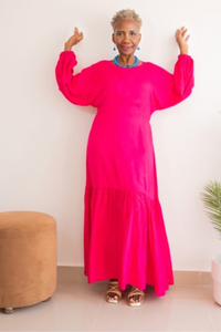 model wearing a bright pink dress with a plain background posing