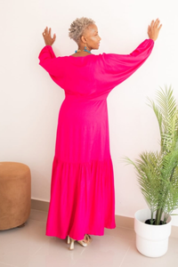 model is showing  the back of a  bright fuchsia, dolman sleeve long dress